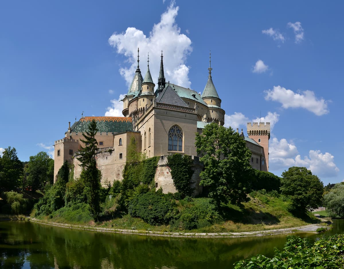 The turrets of Bojnice Castle above its moat and park